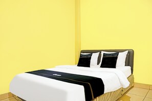 A bed with a black and white bedspread, a grey headboard, and a yellow wall. - Hotel O Bandar Lampung Near Teropong Kota Bukit Cindy Formerly Divka Residence (Bandar Lampung)