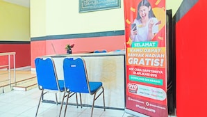 A hotel reception area with a red wall, a framed certificate, and a promotional poster for OYO Hotels. - Hotel O Bandar Lampung Near Teropong Kota Bukit Cindy Formerly Divka Residence (Bandar Lampung)