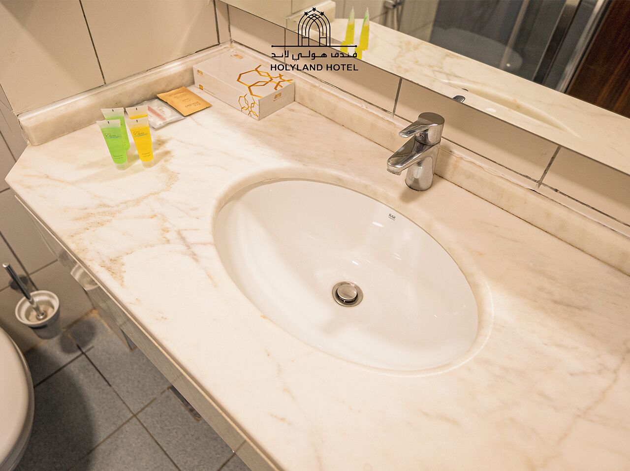 Ein Badezimmer mit einem weißen Waschbecken, einem Spiegel und Pflegeprodukten auf der Ablagefläche.
