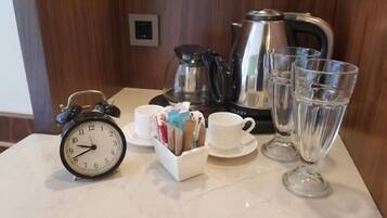 A table with a clock, cups, a teapot, and glasses.