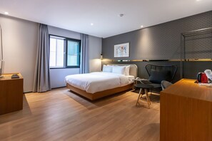 Een moderne hotelkamer met een groot bed, een bureau, een stoel en een raam met gordijnen.