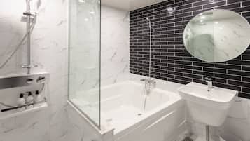 Deluxe tweepersoonskamer | Badkamer | Een bad/douchecombinatie, een diep bad, gratis toiletartikelen