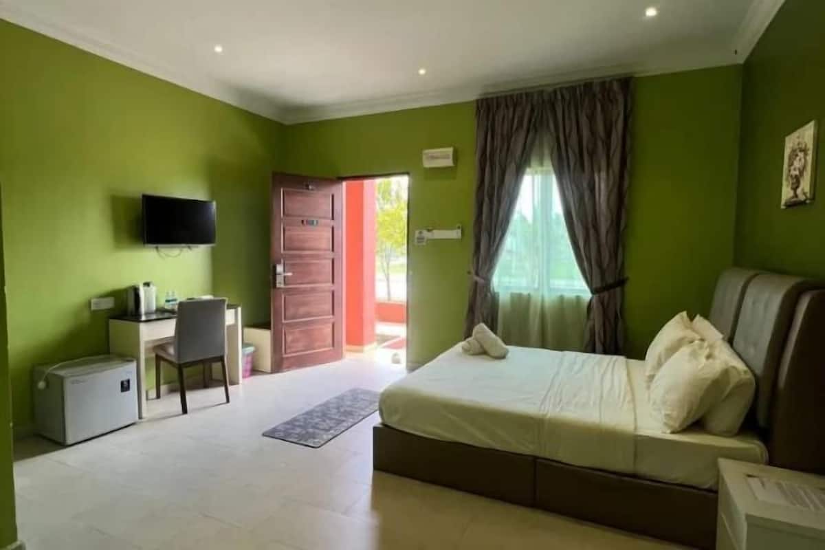 A bedroom with a bed, a desk, a chair, a television, and a window with curtains.