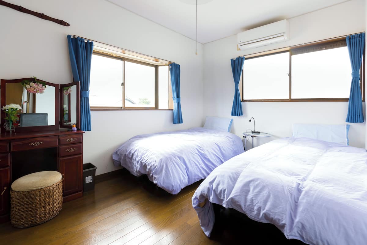 A hotel room with two beds, a dresser, a mirror, and a window with curtains.