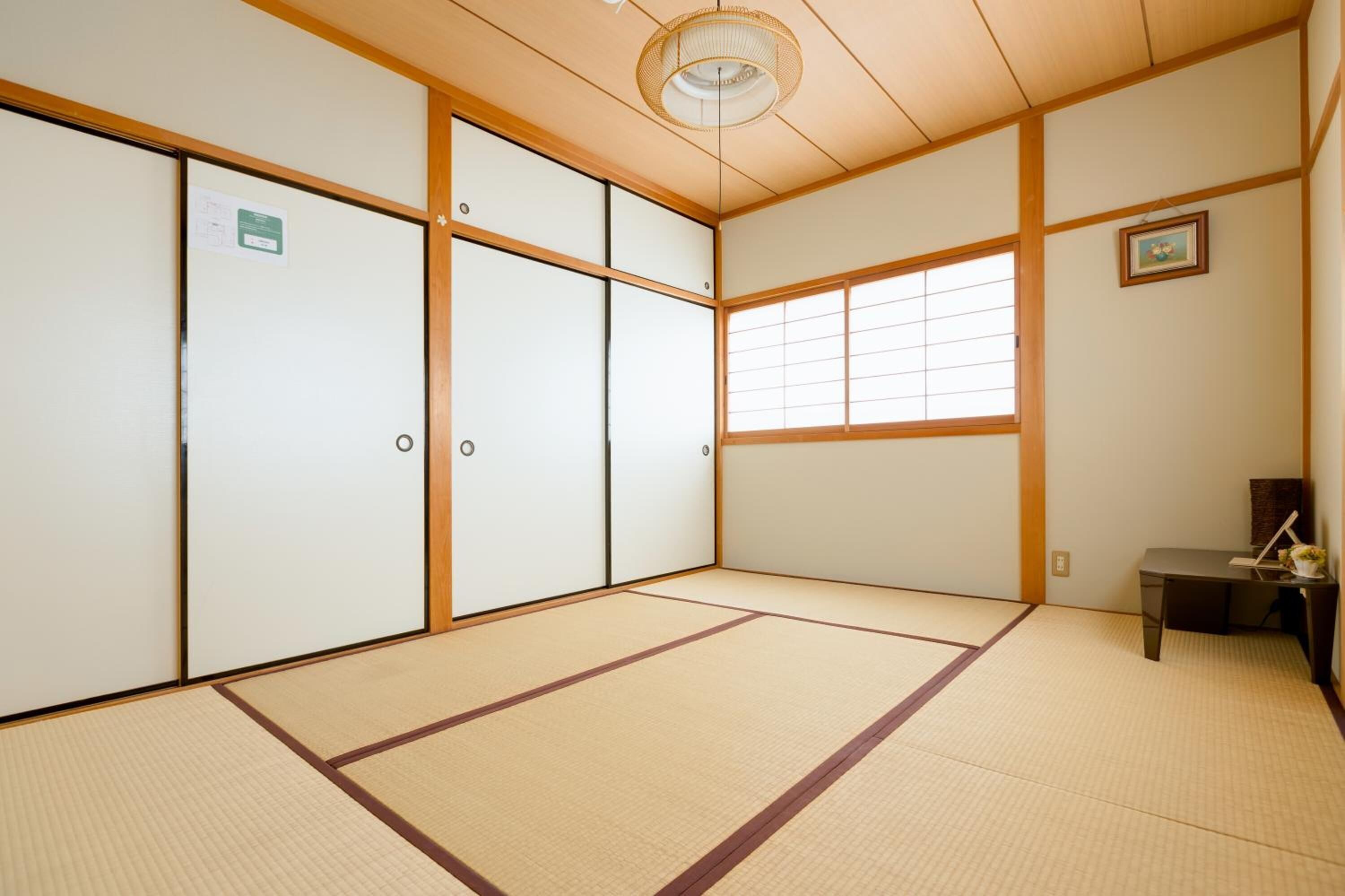 A traditional Japanese room with tatami flooring, sliding doors, and a small desk with a lamp.