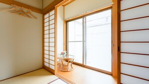 A traditional Japanese room with tatami flooring, a sliding shoji screen door, and a small table with a vase. - A&Z guesthouse (Kaizuka)