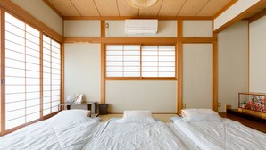 A traditional Japanese-style room with tatami flooring, shoji screens, and a futon bed arrangement. - A&Z guesthouse (Kaizuka)
