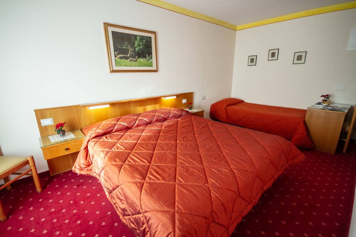 A hotel room with a large bed, a desk with a chair, and a small table with a vase.