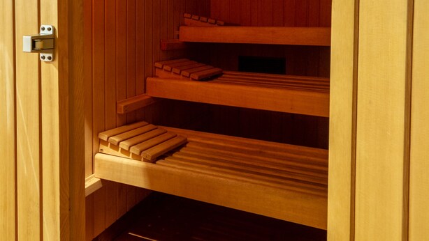 A sauna with wooden benches and a clock on the wall. - Hotel Stella Alpina (Predazzo)