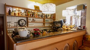 A bar area with shelves of liquor bottles, a coffee machine, and a large white coffee cup. - Hotel Stella Alpina (Predazzo)