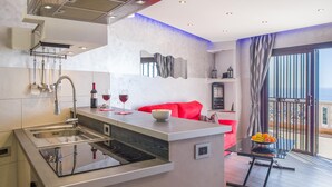 Cozinha moderna com ilha central, sofá vermelho e varanda com vista.