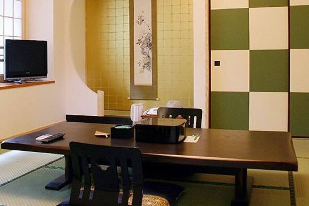 A room with a wooden table, chairs, a television, and a decorative wall.