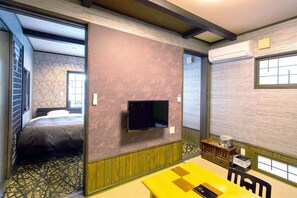 A room with a bed, a TV mounted on the wall, a small table with chairs, and a window with a view. - Yamamomiji (Yufu)
