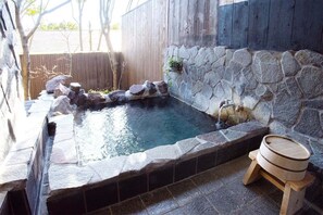 A stone hot tub with a wooden deck and a small wooden barrel. - Yamamomiji (Yufu)