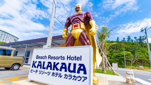 Bordje voor Beach Resorts Hotel Kalakaua met een groot standbeeld van een superheld op de achtergrond.