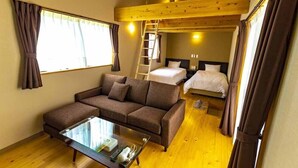 Een gezellige kamer met een bank, een glazen bijzettafeltje, een stapelbed en een ladder.