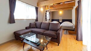Une pièce chaleureuse avec un canapé, une table basse en verre, un lit superposé et une échelle.