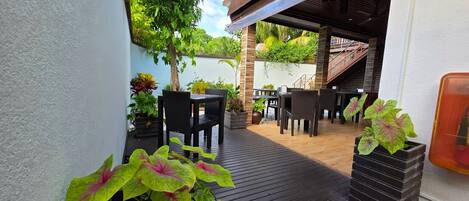 An outdoor patio with wooden flooring, black furniture, and potted plants.