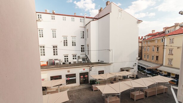 Un patio con mobiliario exterior y un edificio con un letrero que dice 'MENSICA MATERIA'.