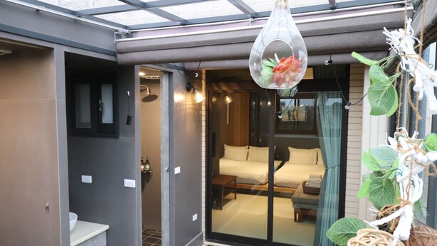 A modern hotel room with a glass door leading to a balcony, a bed with a view, and a hanging plant decoration. - Song Qian Brigade (Lukang)