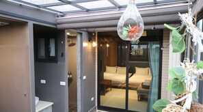 A modern hotel room with a glass door leading to a balcony, a bed with a view, and a hanging plant decoration. - Song Qian Brigade (Lukang)