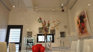 A modern dining area with a glossy table, white chairs, a decorative plant, and a painting on the wall. - Song Qian Brigade (Lukang)