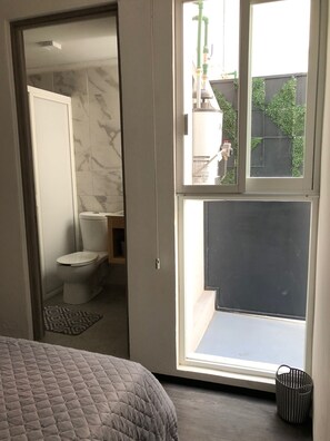 Bathroom features a toilet, window with a view, and a convenient storage basket.