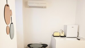 A small kitchenette with a refrigerator, toaster, kettle, and a small table with stools. - Korala Apartments (Piran)