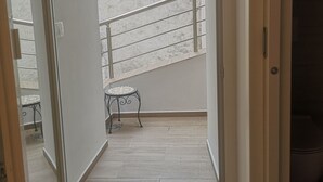 A balcony with a metal railing, a small round table, and a view of neighboring buildings. - Korala Apartments (Piran)