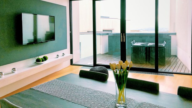 A modern living room with a flat-screen TV, a glass coffee table, and a view of the outdoors through large sliding doors. - Luxury Sea View Apartment (Koper)