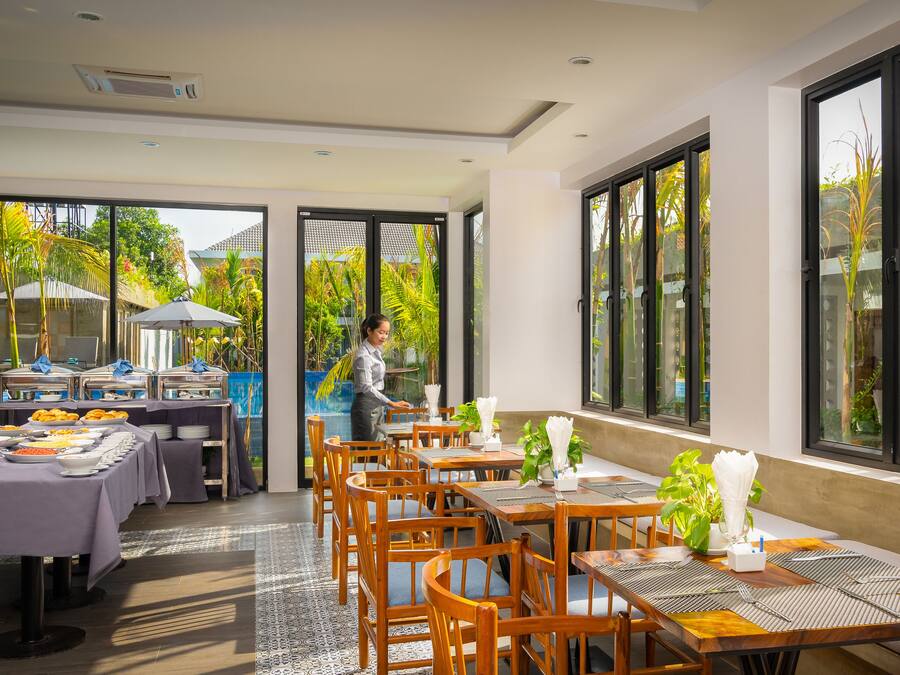 Un restaurante con varias mesas, una zona de bufé y amplias ventanas que ofrecen vistas al exterior.