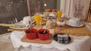 A breakfast setting with a table set for two, including plates, cups, a glass of orange juice, and a variety of pastries. - 2 Chambres Tramontane et Alizé (Jonquerettes)