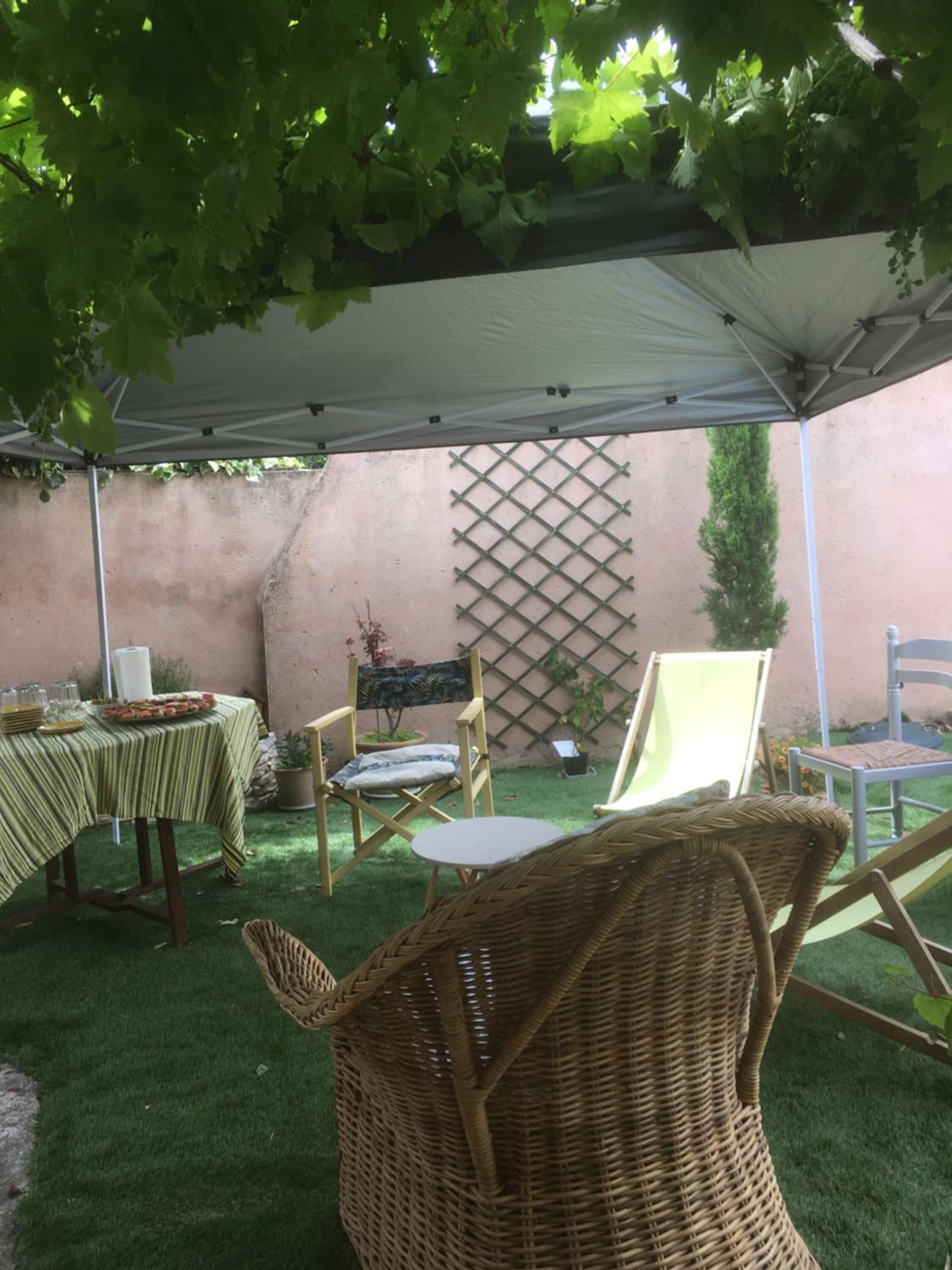 An outdoor patio area with a table set for dining, wicker chairs, and a covered seating area.