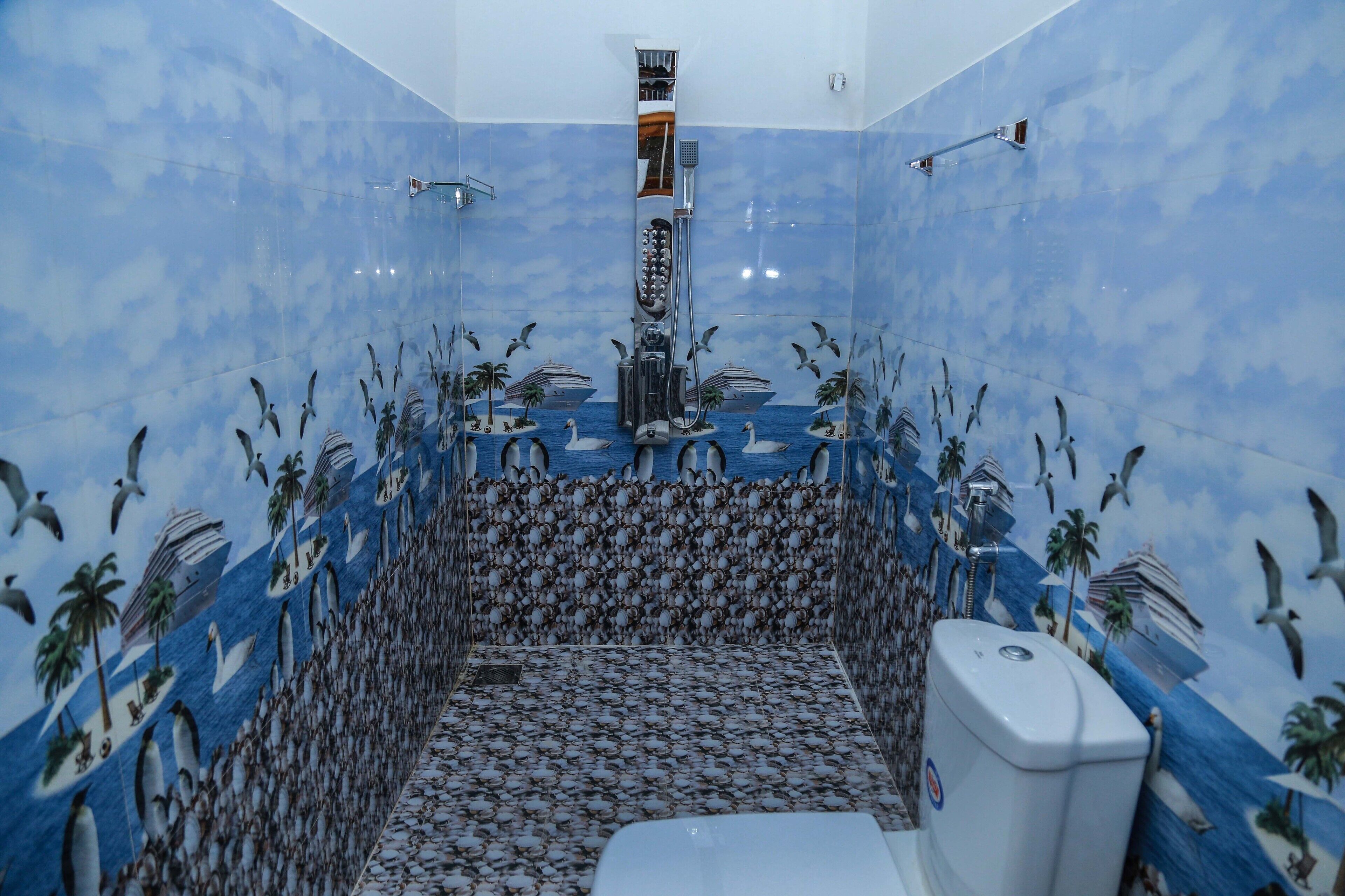 A bathroom with a blue and white tiled wall featuring a mural of swans, penguins, and palm trees.