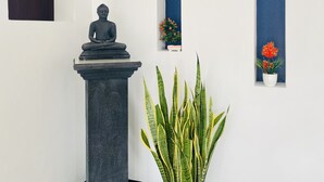 A statue on a pedestal, a potted plant, and two vertical blue panels with floral decorations. - Cinnamon City (Hikkaduwa)