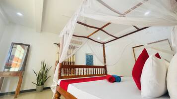 A four-poster bed with a canopy, a potted plant, and a framed picture on the wall.