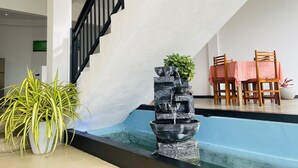 A modern indoor setting with a staircase, a water feature, and a dining area with chairs and a table. - Cinnamon City (Hikkaduwa)