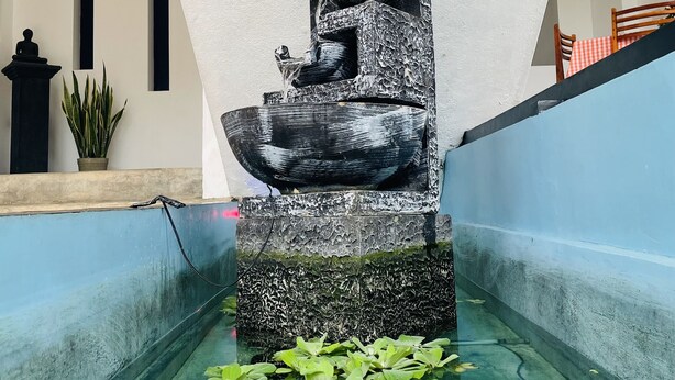 A water feature with a cascading design, surrounded by a pool with water lilies. - Cinnamon City (Hikkaduwa)