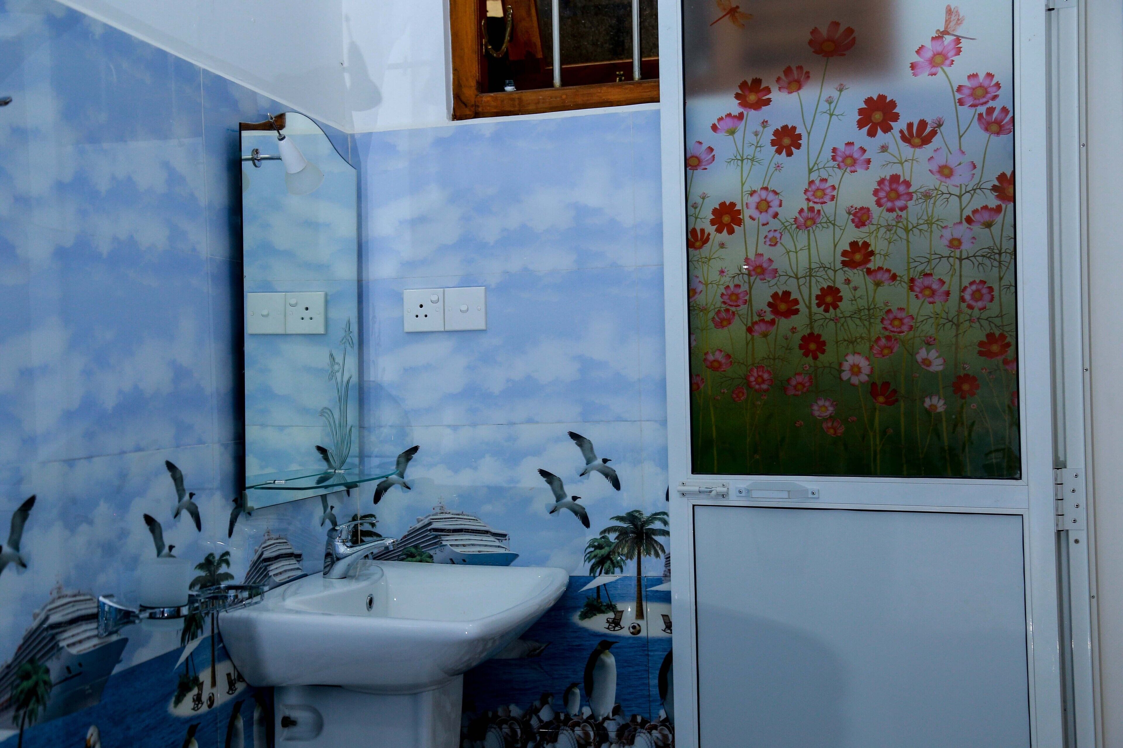 A bathroom with a sink, mirror, and decorative wall tiles depicting seagulls and a ship.