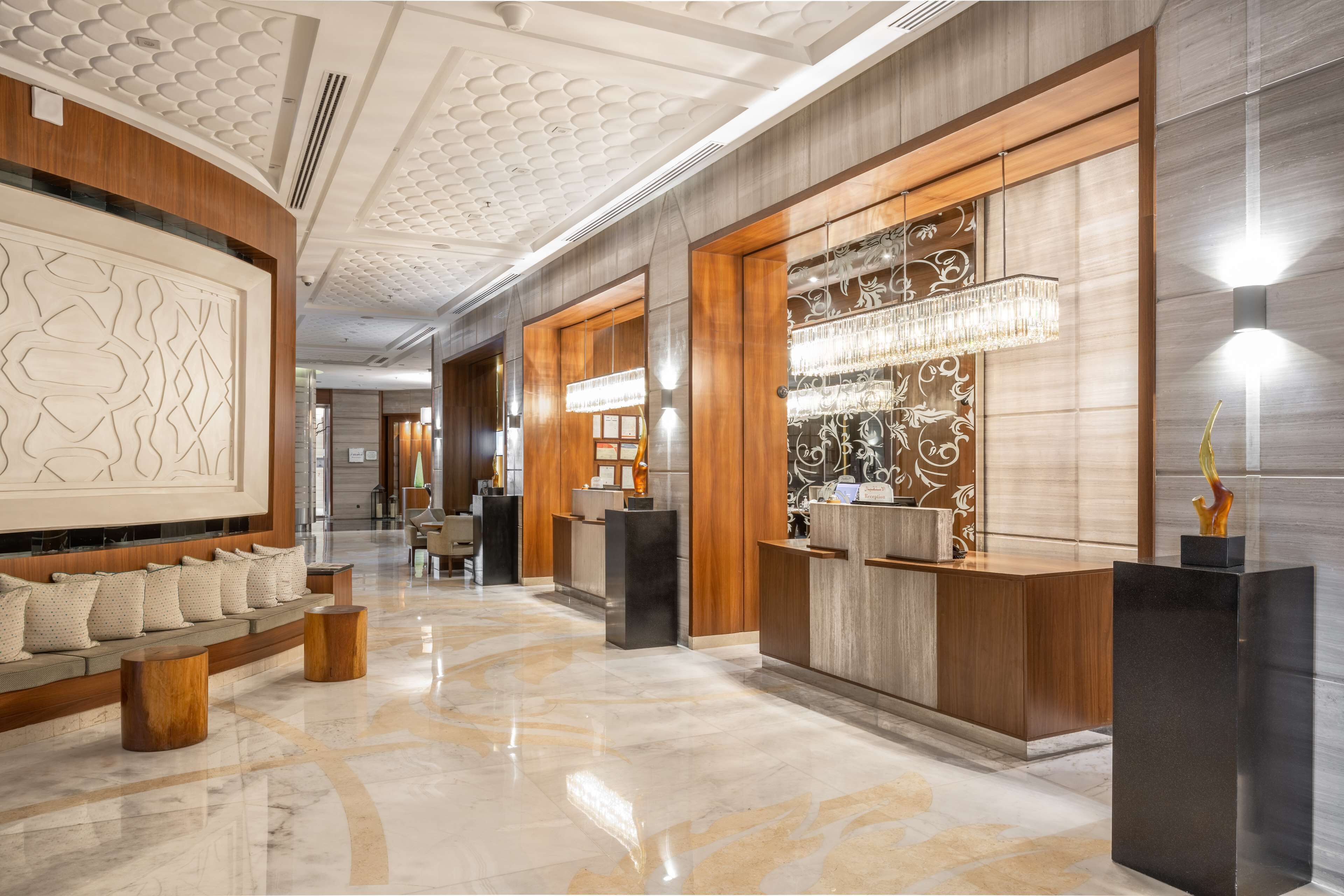A spacious lobby with a reception desk, seating area, and decorative wall panels.