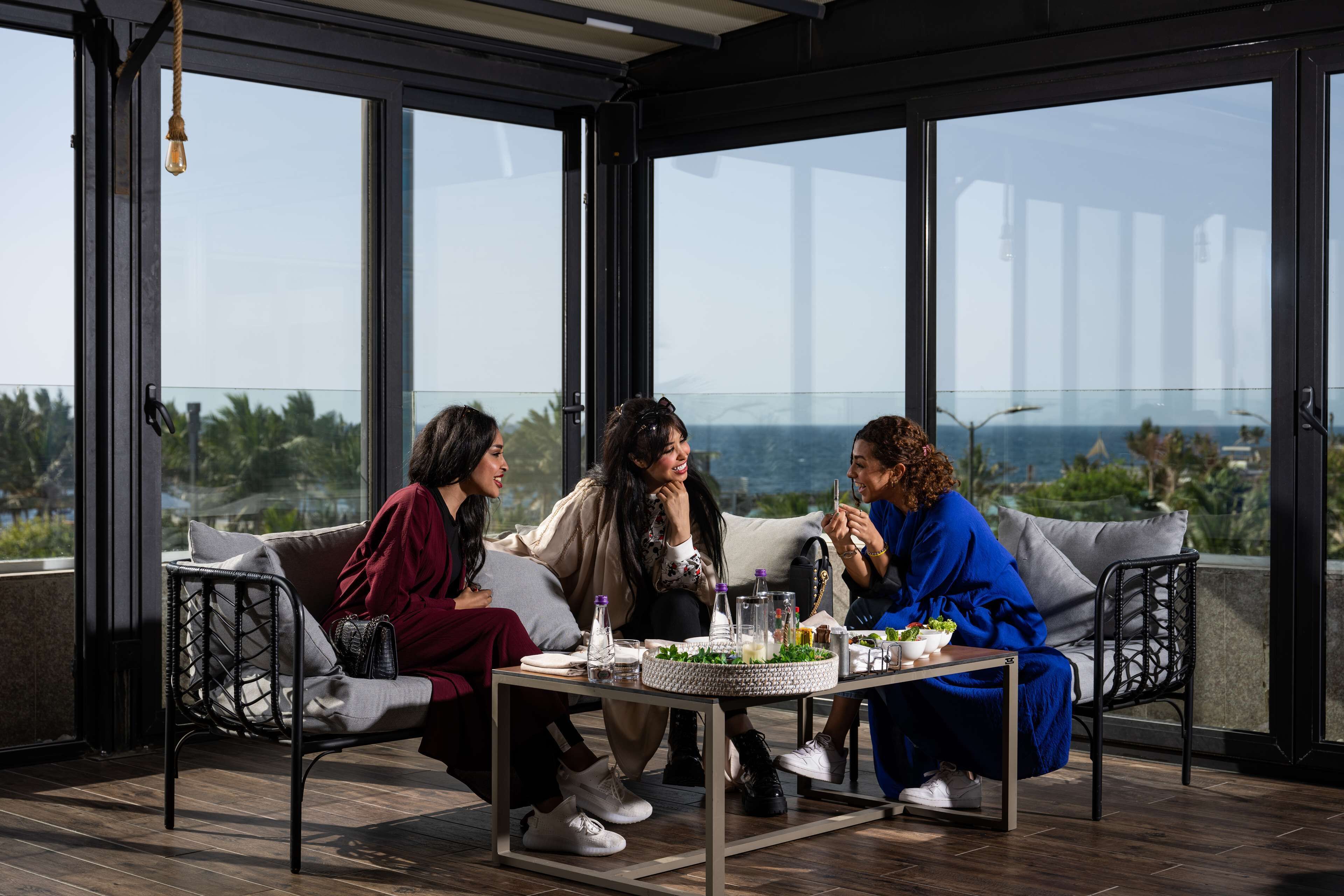 A group of people seated on a balcony with a table in front of them, overlooking a cityscape.