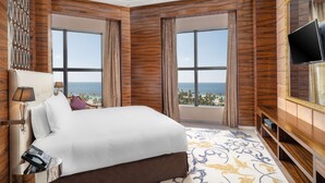 Une chambre d’hôtel avec un grand lit, une télévision et une vue sur la mer.