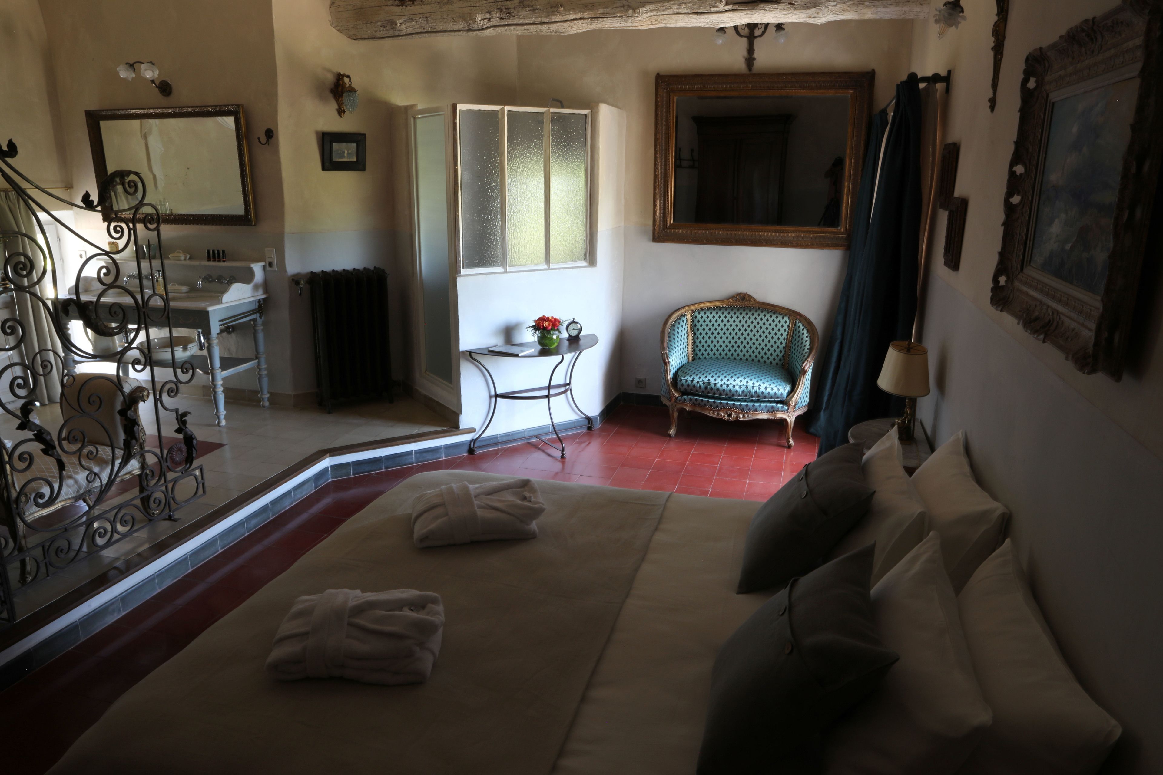 A hotel room with a bed, a sitting area with a chair, a small table, and a window.