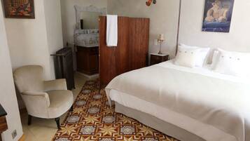 Una habitación de hotel con cama, una silla, tocador con espejo y suelo estampado.