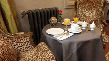 A dining table set with plates, cutlery, and a glass of orange juice.