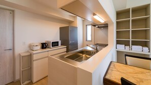 Una cocina compacta con microondas, horno y pileta. Hay una pequeña zona de estar con una mesa y sillas.