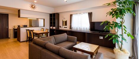 A modern living room with a sofa, a dining table, and a television.