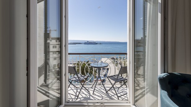 A balcony with a table and chairs, overlooking a body of water and buildings. - Seaview Luxury Retreat (Split)
