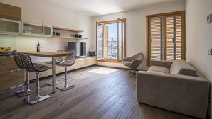 A modern kitchen with a dining area, a sofa, and a large window with blinds. - Seaview Luxury Retreat (Split)