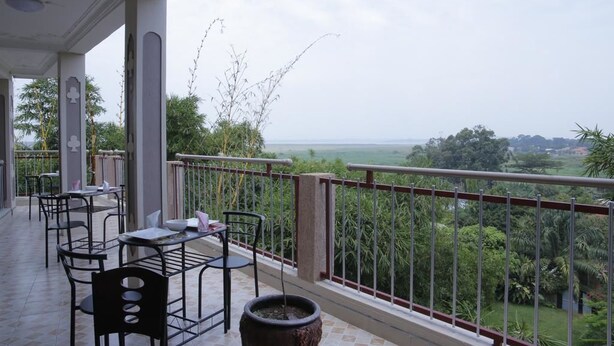 An outdoor terrace with tables and chairs, a potted plant, and a view of a lush landscape. - Crystal Hotel Apartments Entebbe (Entebbe)